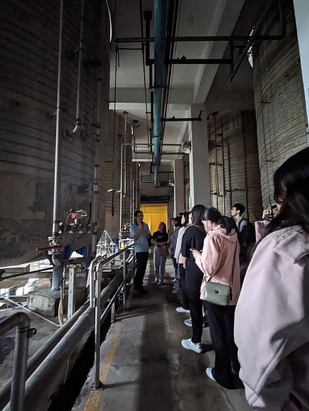 花蓮酒廠物料課簡凱偉課長帶領同學在發酵槽外說明製程。