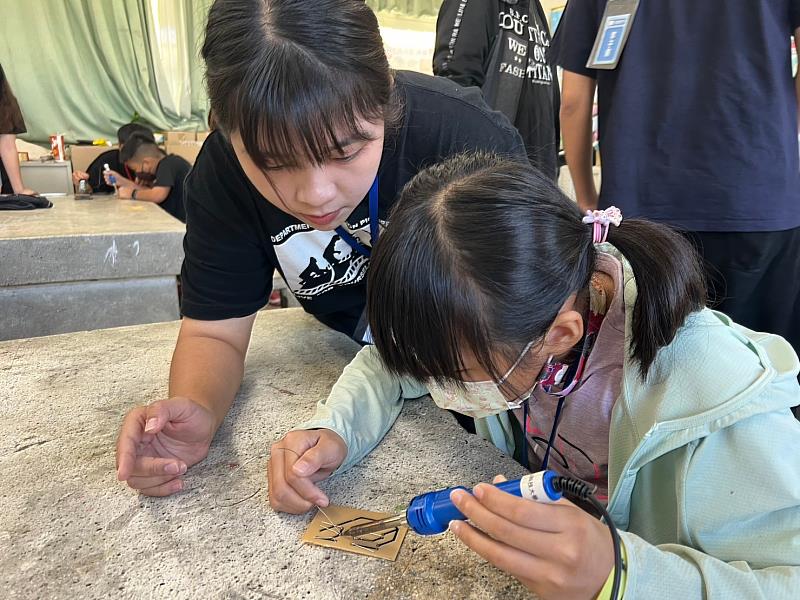 學生指導水燦林國小孩童進行電路板焊接