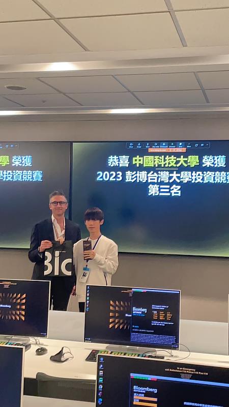 在全台頂尖大學競爭下，中國科大財金系三年陳東洋同學榮獲「2023年彭博Bloomberg台灣大學投資競賽」全國第三名。彭博主管(左)頒發獎盃給陳東洋同學(右)。（圖／中國科大提供）