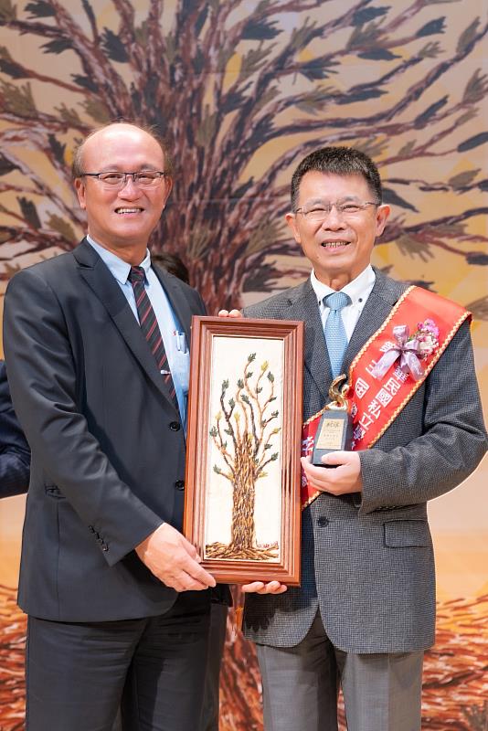 東吳大學校長潘維大(右)榮獲傑出校長獎，教育部次長林騰蛟(左)頒贈阿美族的樹皮雕畫，象徵私校永續百年樹人