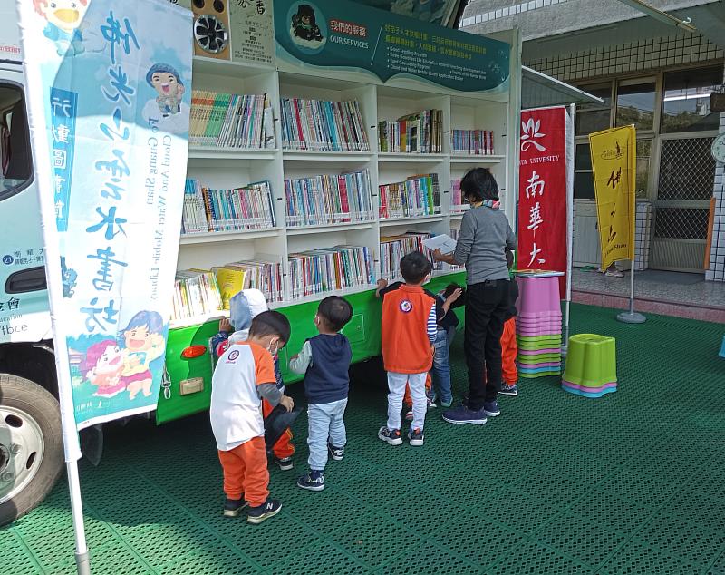 南華大學雲水書車至幼兒園推廣閱讀，孩童聽完故事後，在書車挑選繪本閱讀。