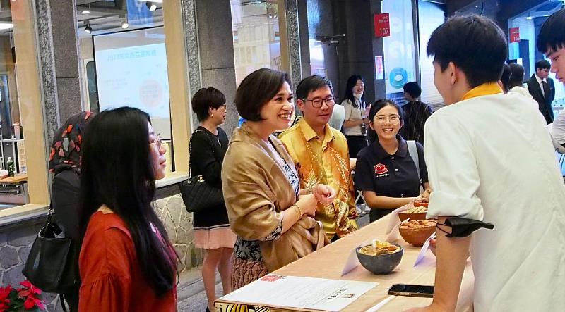 馬來西亞友誼及貿易中心首席代表艾思妮花(左二)，於開平餐飲國際部的馬來西亞國際週展攤認真聆聽學生分享。開平餐飲學校/提供
