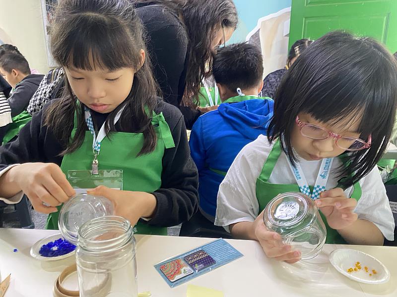 Children brought used glass jars from home and use recycled glass beads to create sustainable mosaic lamps.