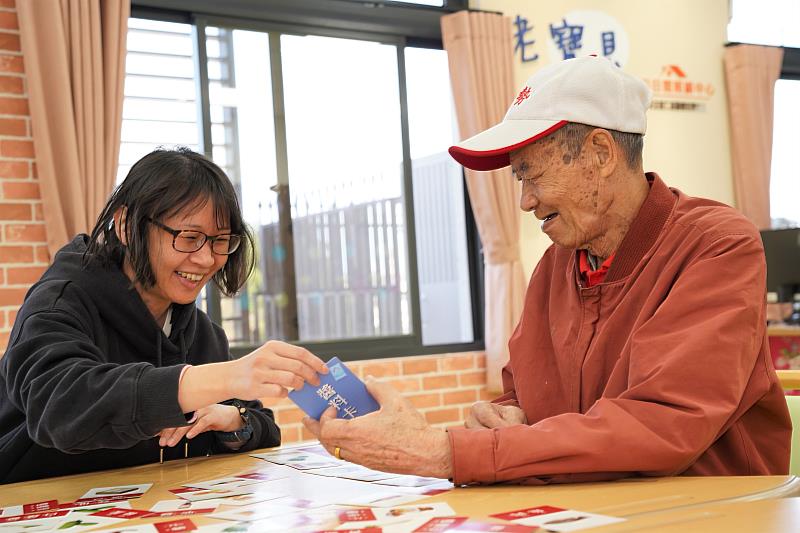 官網-湖口老寶貝日照中心的專業人員細心教導長輩玩桌遊。
