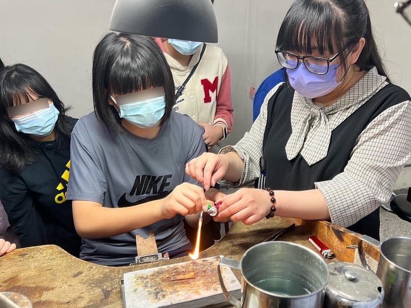 金工職類訓練師(右)引導棕樹學園少女體驗火槍燒熔金工焊接