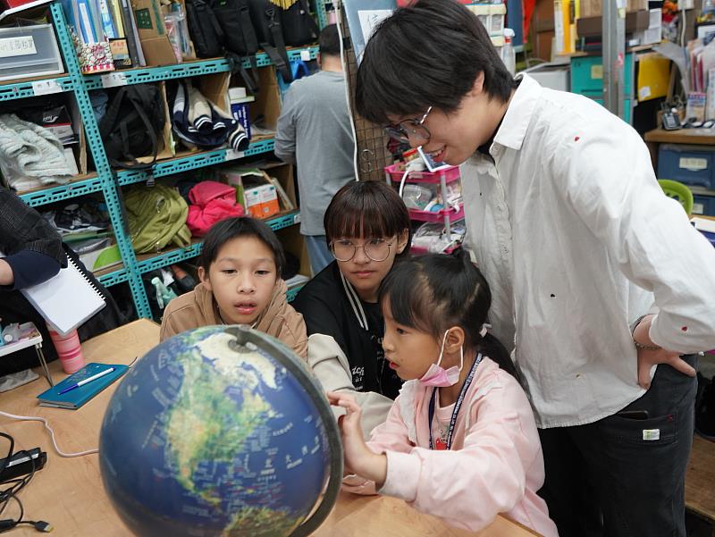 五味屋孩子從地球儀上找尋國際生們的家鄉位置。