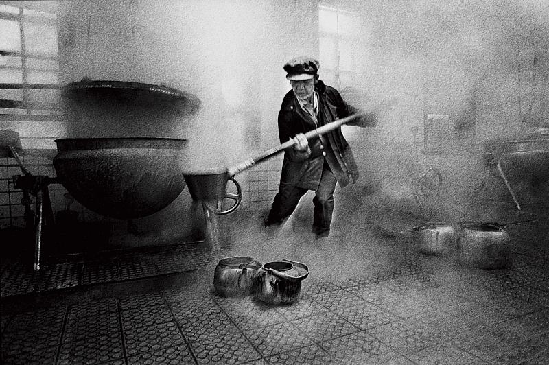 每天至蒸氣瀰漫的公炊廚房燒水、提壺熱水，是過去樂生居民揭開一天序幕的儀式。周慶輝，《行過幽谷》，〈輕度精神病患李亞育是一位熱心的挑水義工〉，1992，國家攝影文化中心