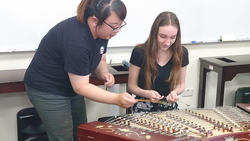 美國三一大學師生蒞南華大學民音系進行移地學習，民音系研究生廖方琦(左)指導揚琴演奏。