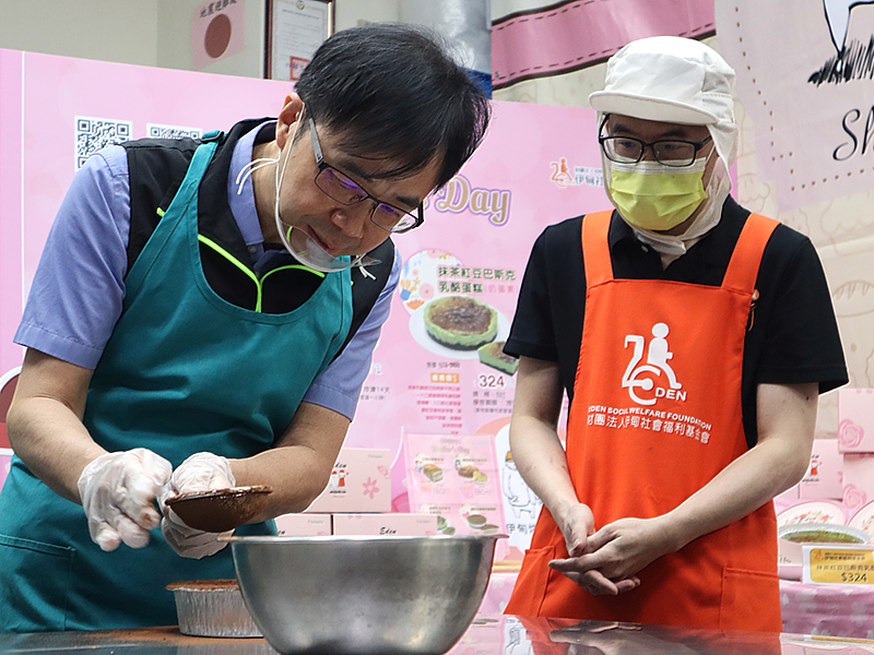 桃園市政府勞動局副局副局長周賢平在伊甸庇護員工小錦帶領下,完成可愛的提拉米蘇蛋糕。(伊甸基金會提供)