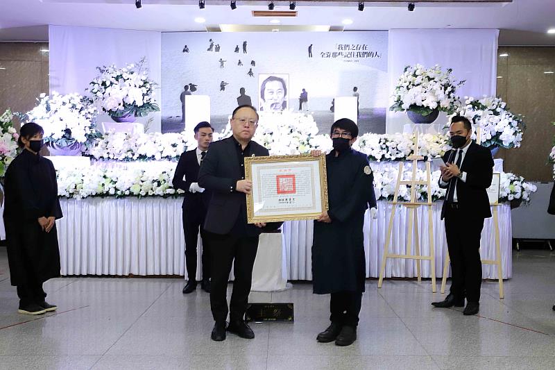 文化部長史哲（左）代表頒贈總統褒揚令，由張照堂長子張世和（右）代表受贈，表彰攝影家張照堂對於臺灣影像藝術發展與教學的重要貢獻。