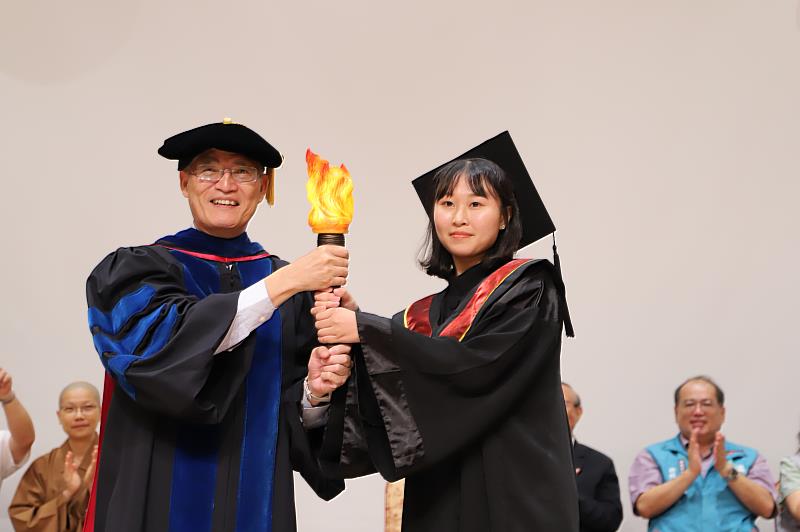 南華大學舉辦畢業典禮，高俊雄校長將象徵「奮起、飛揚、茁壯、放光」的智慧火炬，傳遞給畢業生。