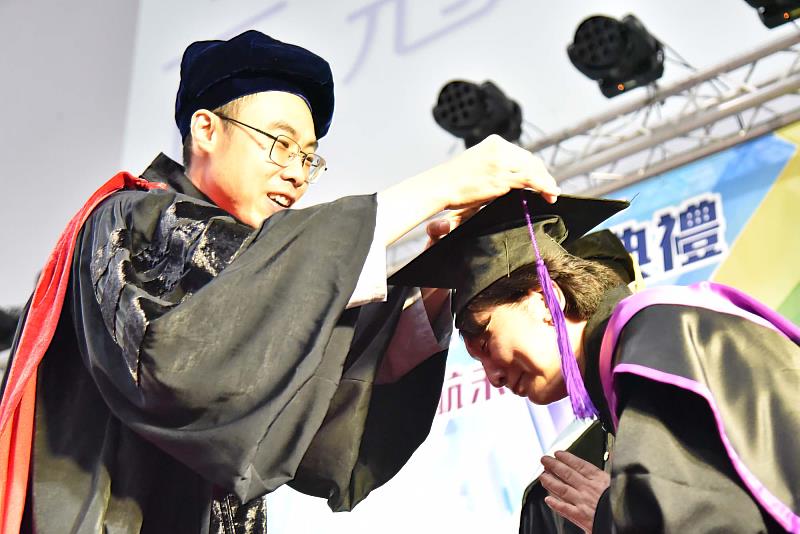 華梵大學佛教藝術學系陳俊吉主任（左）為畢業生正冠撥穗。