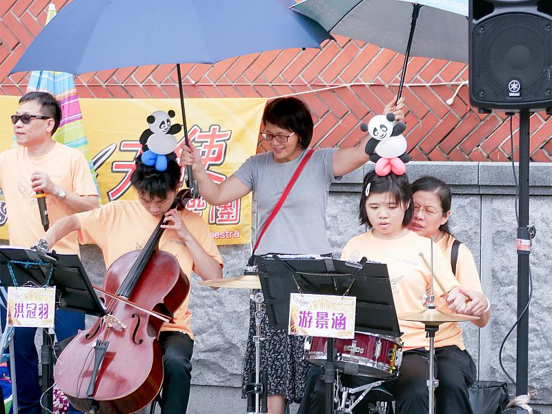 Angel-6樂團家長們不畏風雨，撐起大傘保護著孩子們
