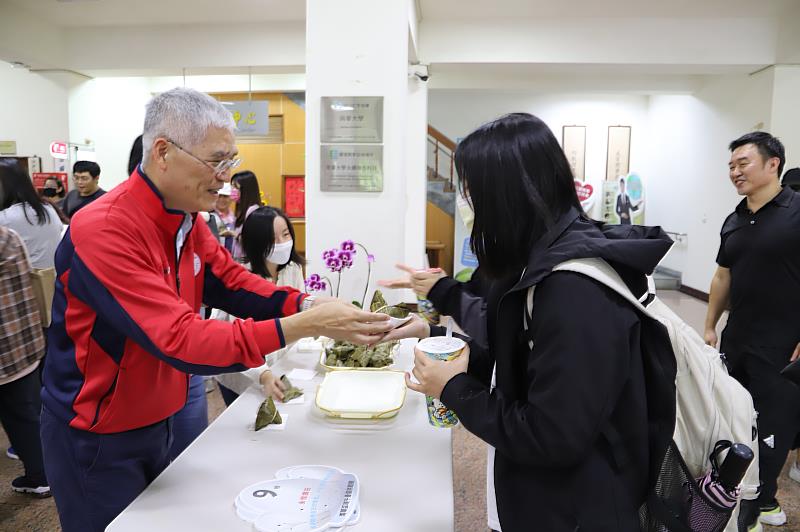 南華大學舉辦「不給糖就疊蛋」端午活動，高俊雄校長(左)發送粽子給學生。