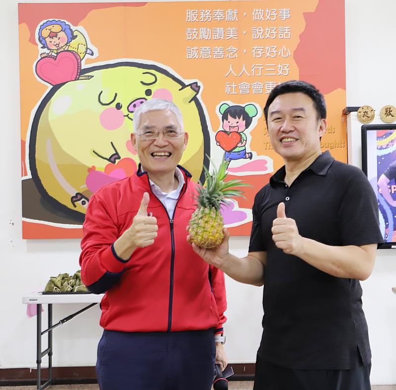 南華大學舉辦「不給糖就疊蛋」端午活動，高俊雄校長(左)贈送象徵「好運旺旺來」的鳳梨給學務處。右為何應志學務長。
