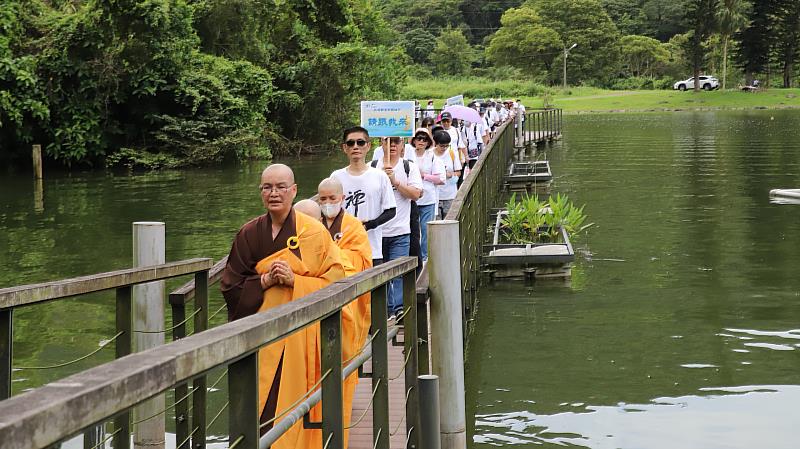 眾人走在龍潭湖上的步道，讓佛號與水波共振，願觀音的慈悲力量守護湖邊生態。（靈鷲山佛教教團提供）