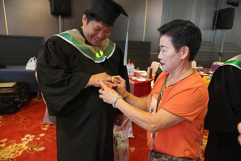 畢業生黃文毅(左)的母親特地打了三錢重金戒子當場為兒子戴上當賀禮