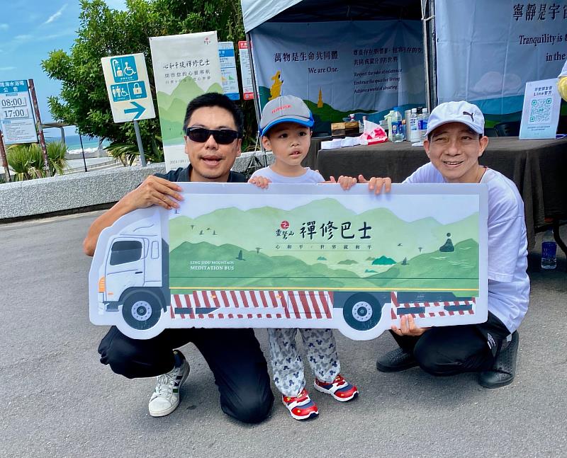 親子和禪修巴士的看板開心合照。(靈鷲山佛教教團)
