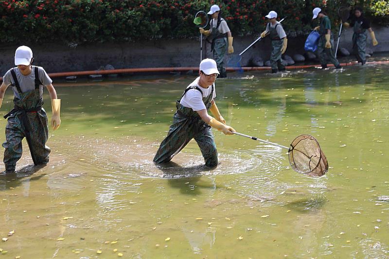 學生在踩在湖底淤泥裡努力撈魚