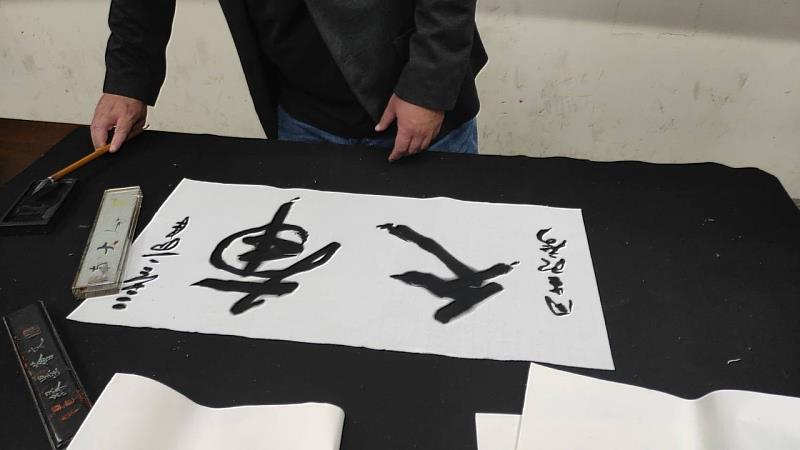 於博士在講座結尾，以古隸現場揮毫書寫「南大」二字，展現深厚學養與揮灑自如的筆法