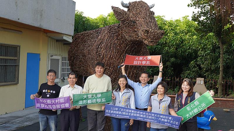 大葉大學吉田敦老師(左三)與賴建源老師(右三)，一起在貢旗社區中心兒童公園的藤牛裝置藝術前合影