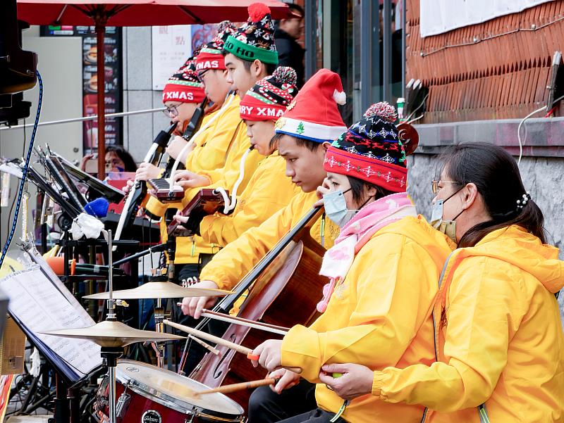 樂團七位成員——鼓手景涵、口風琴手政原與韋婕，電吹管手哲民與新民，電子琴鍵盤手麒瑋，大提琴手冠羽——各自專注地拿起樂器，奏響充滿節慶氛圍的旋律。