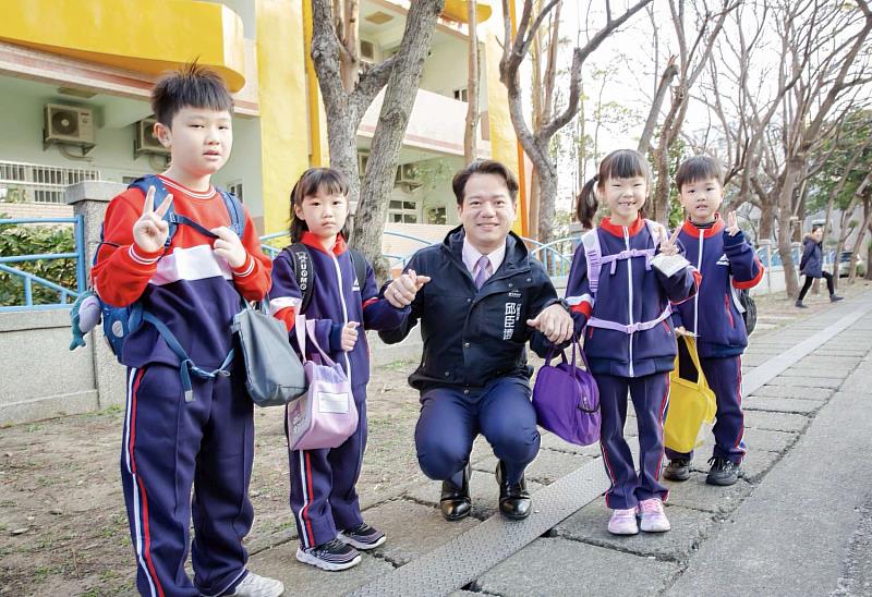 邱臣遠代理市長於人行道陪同學童步行進入校門。