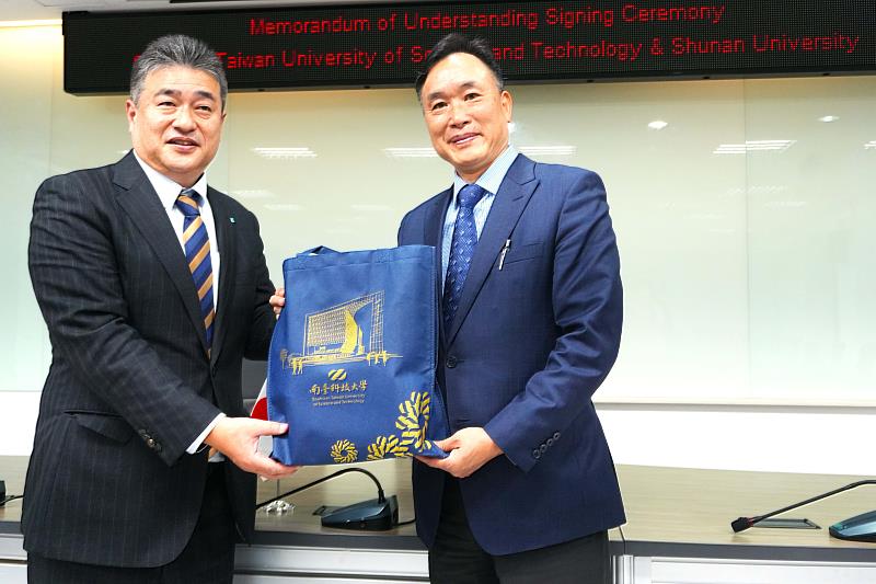南臺科大黃能富校長（右）與日本周南公立大學人間健康科學部福祉學科梅田勝利系主任（左）互贈紀念品，為兩校合作寫下新篇章。