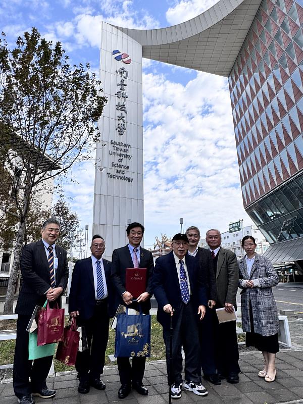 南臺科技大學張信雄董事長與日本周南公立大學團隊在宏偉的磅礴大樓前合影。磅礴大樓是南臺科大的地標之一，也象徵著學校的發展與活力。