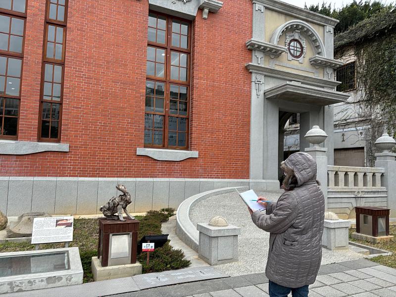 民眾在冷風中聚精會神地描繪展出的漂流木創作