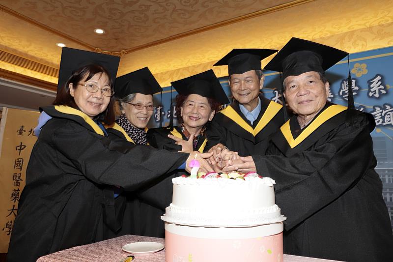 13屆藥學系學長姊穿著學士服開心切蛋糕，歡慶畢業50周年紀念。