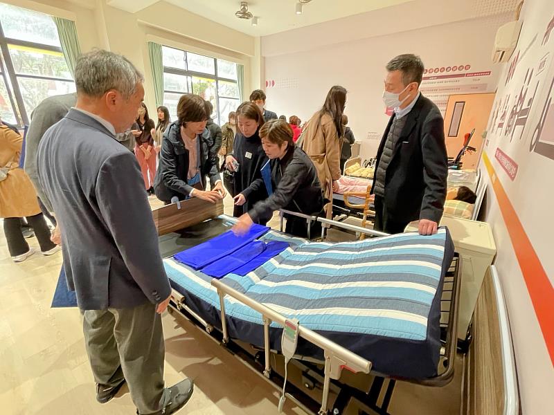 參訪團實地體驗「樂齡自然照顧訓練室」的設備，對智能AI均壓床墊感到非常有興趣。
