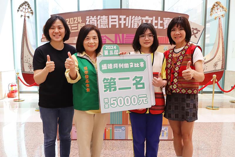 張榮發基金會執行長鍾德美(左二)頒發獎金給道德月刊徵文比賽偏鄉組第二名高彭喜恩(右二)同學,並與烏來國中小校長蔡依玲(右一)、指導老師王美宜(左一)合影留念。