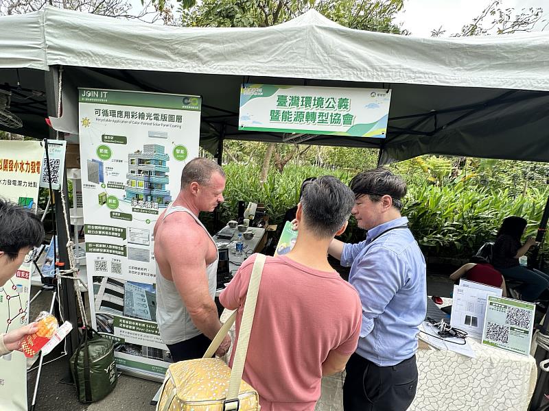 「在一起永續」展示可循環應用彩繪光電圖層技術，吸引來自國內外民眾駐足交流。產品總監許恩斯（右）熱情向現場參觀者說明技術特色，強調如何結合建築外觀與太陽能創能，推動淨零建築實踐，展現台灣綠能創新向國際接軌的堅實步伐。（圖片由在一起永續科技提供）