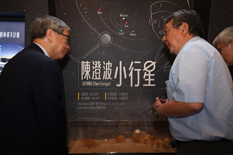 國立中央大學天文研究所長周翊(右)藉「陳澄波小行星微型展」中的鹿林天文臺模型,向文化部長李遠(左)說明其運作情況。