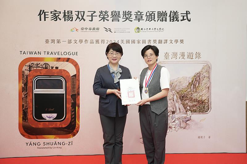 臺中市文化局長陳佳君（左）代表盧秀燕市長頒發榮譽獎章給楊双子（右）