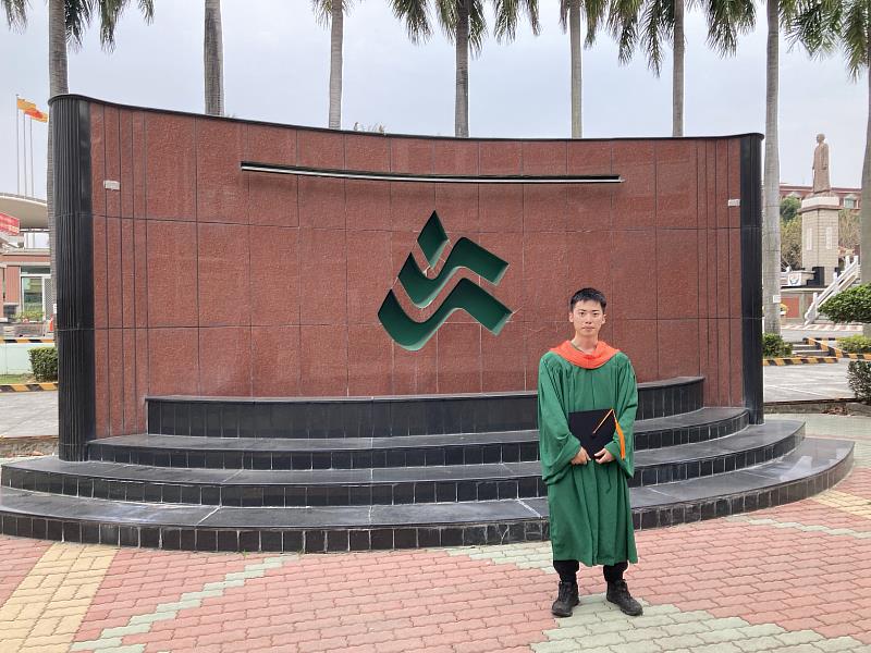 張修維身穿碩士服於校園留念