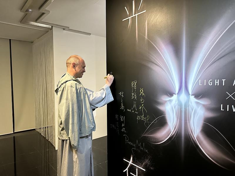 呂天恩神父在「光在萬物」特展展板上簽名。（圖由世界宗教博物館提供）