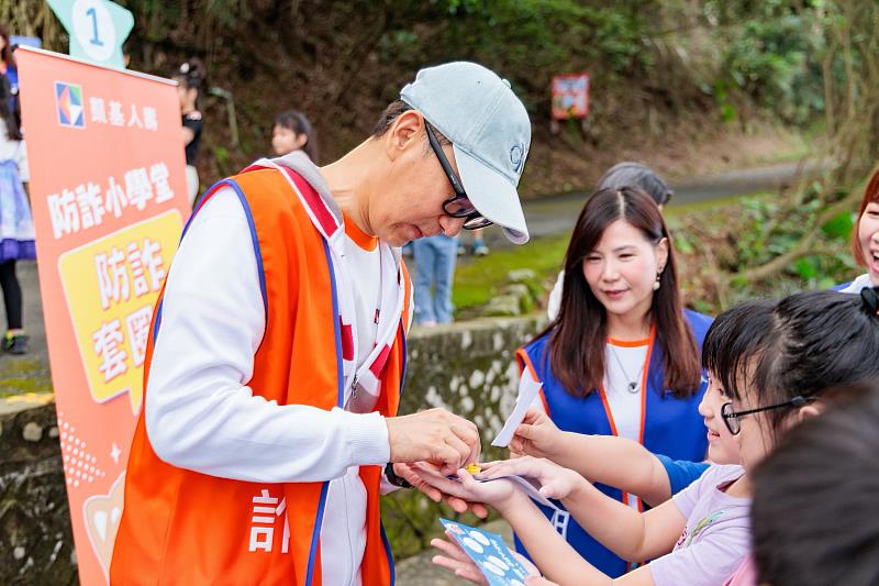 圖2:防詐小學堂設計了生動有趣的闖關遊戲,王銘陽董事長(左一)擔任關主,孩子們要知道正確防詐知識,還得手腳並用才能成功過關,在寓教於樂中建立觀念。