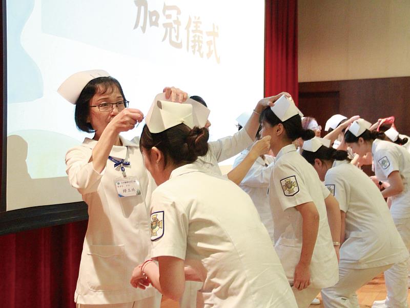 元培護理系年度加冠典禮-，師長們細心為學生戴上象徵專業的白帽