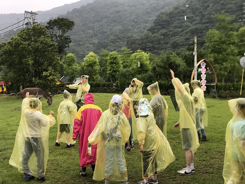 學生在雨中帶小朋友做暖身操。
