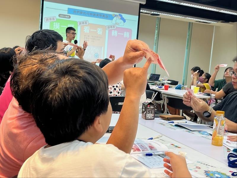 大小朋友聚精會神觀察百元鈔票。