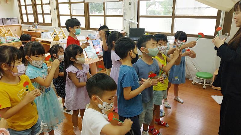 南華大學民音系學生隨著雲水書車下鄉至幼兒園，小朋友拿著手作康乃馨唱兒歌。