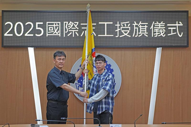 中華大學學務長閻克勤授旗給國際志工團團員林圭彥，祝福行程順利平安。
