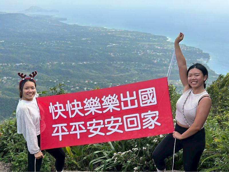 實習生謝慈芳在聖露西亞上山下海時，總是拿出自備的「快快樂樂出國，平平安安回家」紅布條合照