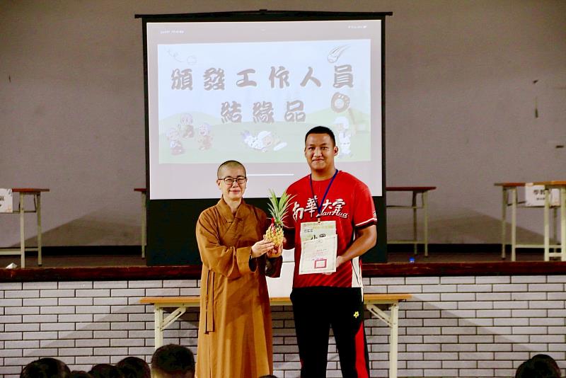 員林講堂與南華大學共推三好,兒童夏令營歡喜結營,營主任妙玄法師(左)頒發結緣品予活動工作人員,由值星官代表受贈。