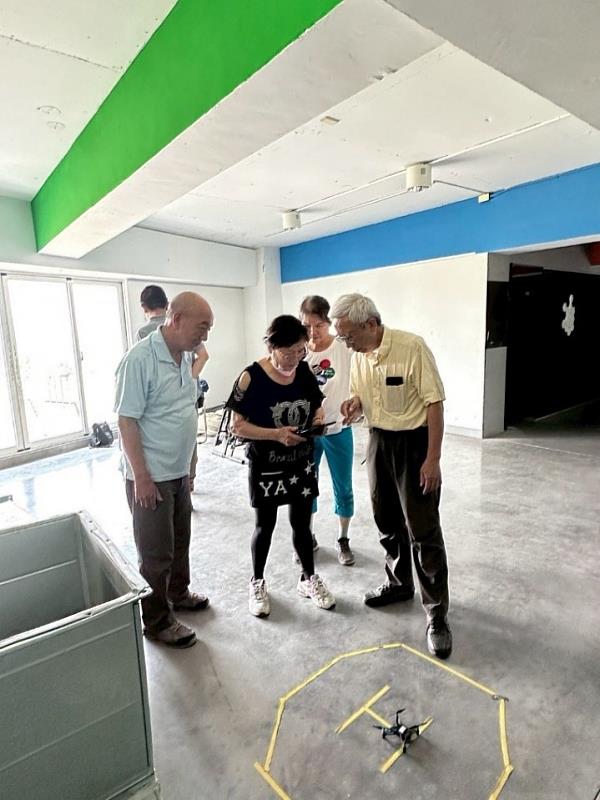 圖說：無人機訓練發展中心執行長張偉國副教授指導樂齡學員操控無人機。（圖/中信科大提供）