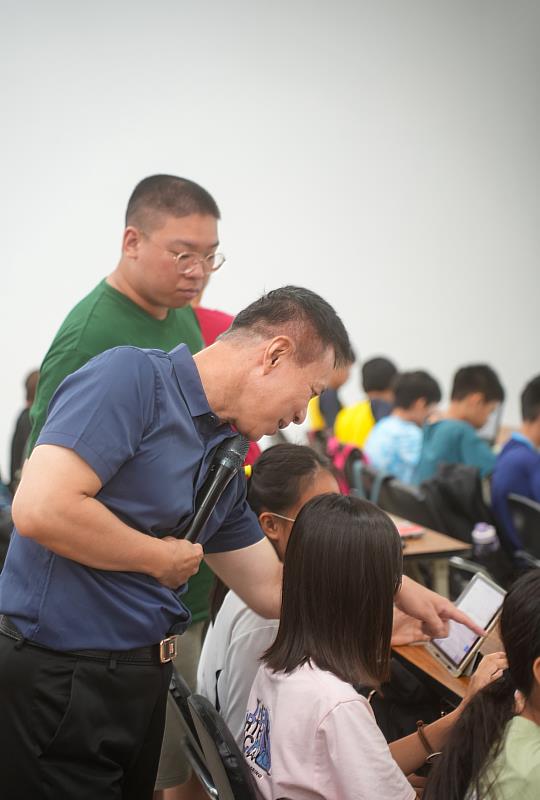 世新大學新聞系系主任許志明指導孩童使用生成式AI技術,啟發創造力並開拓科技應用新視野。(世新大學提供)