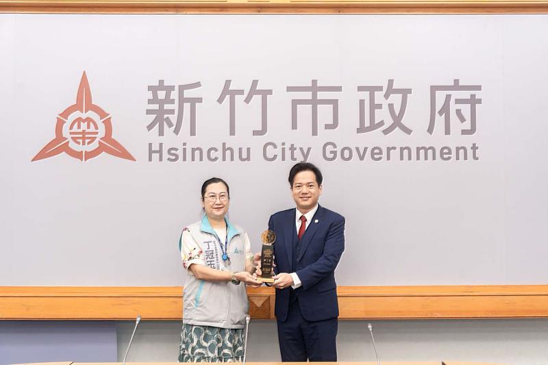 新竹市長期照顧管理中心主任丁冠玉獻獎予代理市長邱臣遠。