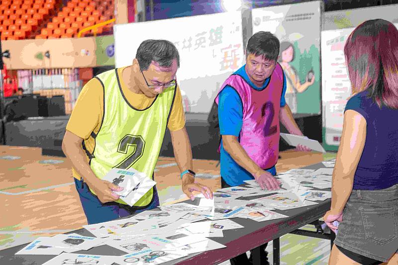 參賽者正在認真挑選桌面上陳列的各種圖卡，這些圖卡代表不同的森林巡護裝備。